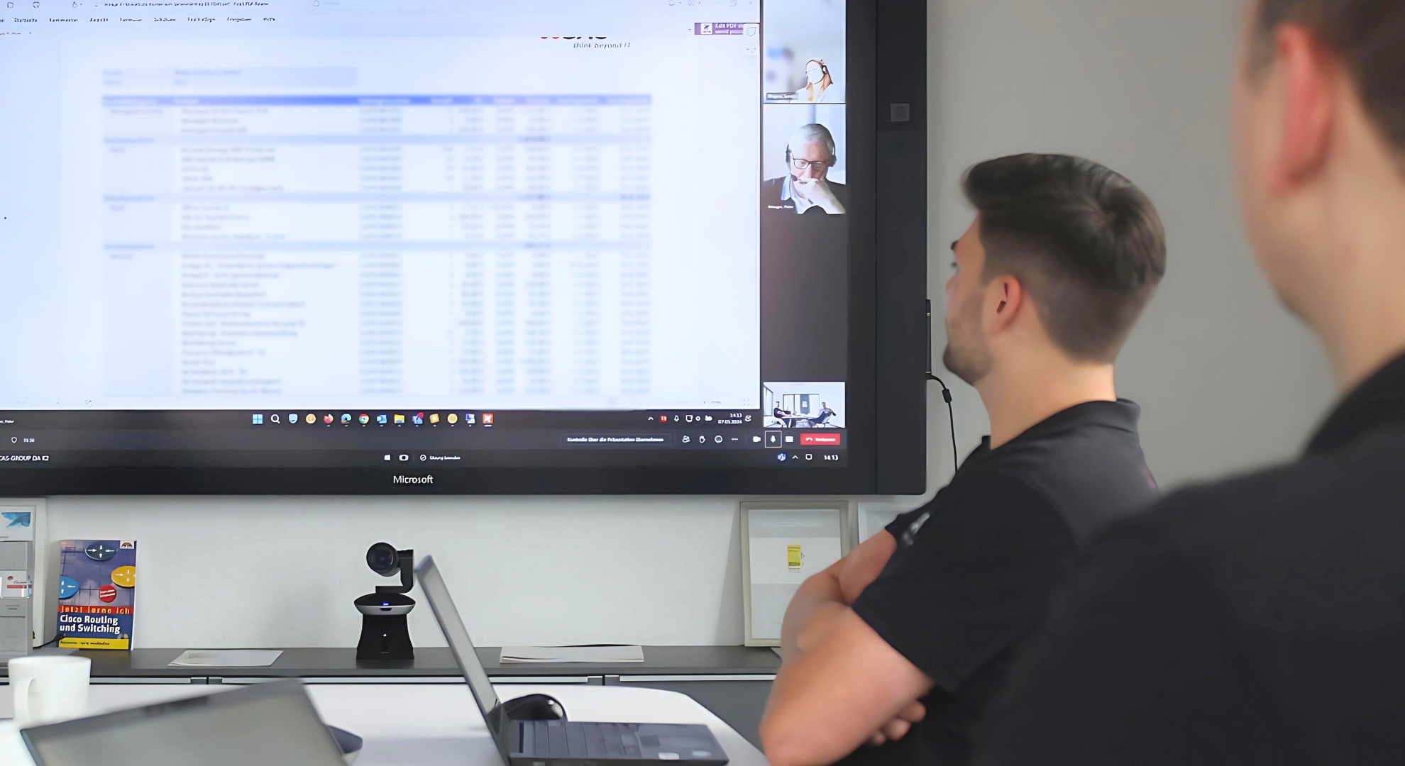Foto von zwei SAC Mitarbeitern welche in einem Besprechungsraum sitzen und via Teams mit weiteren Mitarbeitern eine Besprechung halten