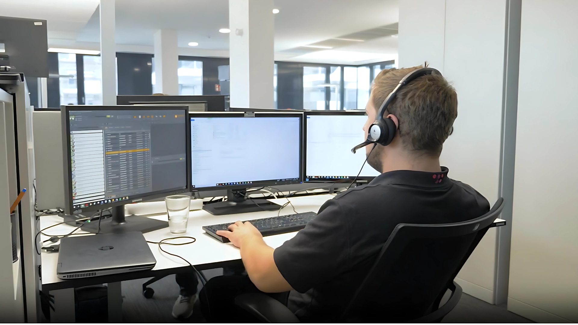 sac_beitragsbild_aufgaben it-abteilung Ein SAC Mitarbeiter der an einem Schreibtisch mit mehreren Bildschirmen sitzt und über Headset einem Kunden bei einem IT-Problem hilft.